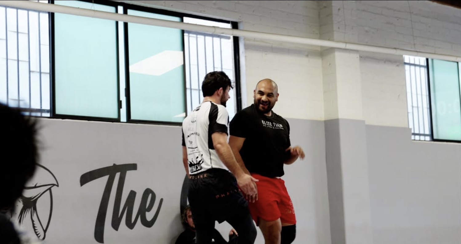 Two members laughing beside the hand-painted 'The' script mural